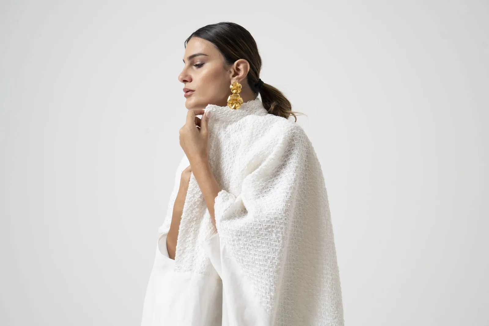 Model in an ivory textured cape against a soft studio backdrop