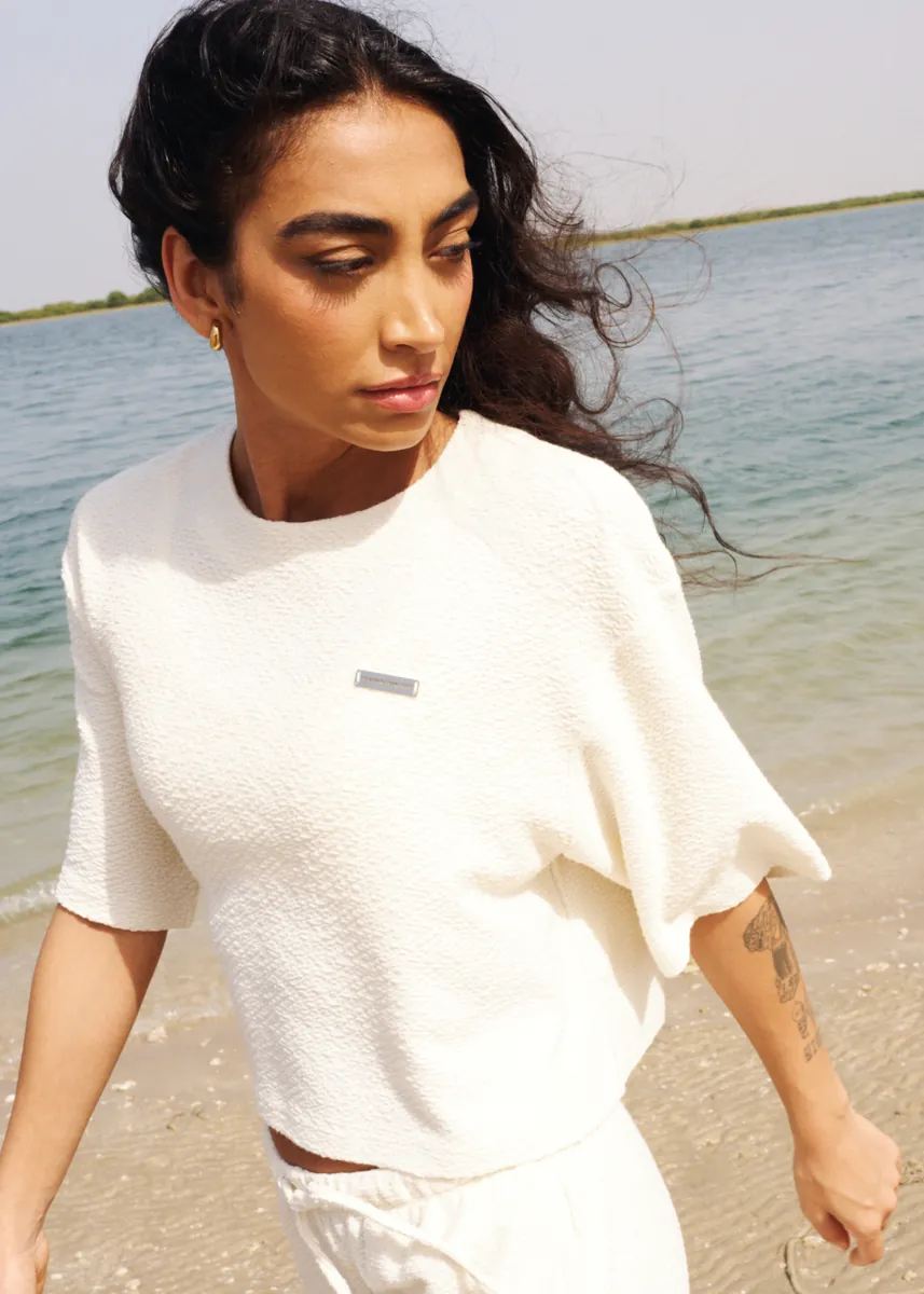 Model in an ivory knit top on the beach